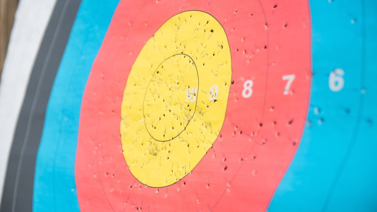 Detailed view of a colorful archery target with numerous arrow holes, showcasing precision